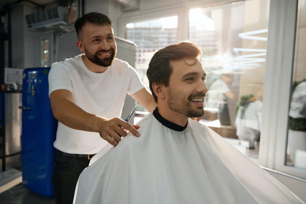 Happy male client of hair salon looking contented with haircut